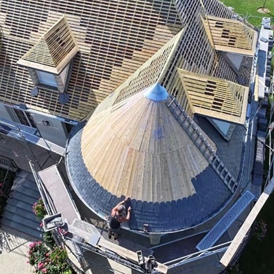 Rénovation complète d'une toiture complexe : pose d'ardoises naturelles sur tourelle circulaire et lattage neuf. Excellence artisanale par Protec Toiture.