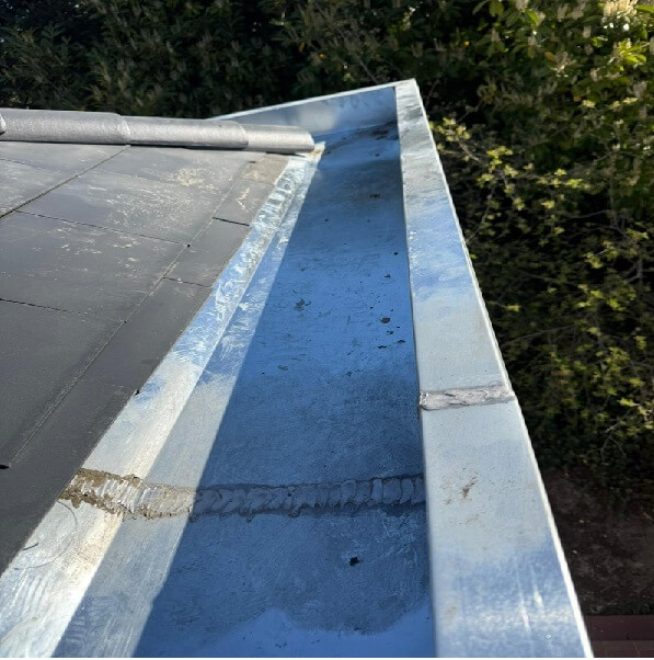 Réparation de fuite sur corniche en zinc et vérification de l'étanchéité de la toiture en ardoises. Service de dépannage rapide par Protec Toiture.